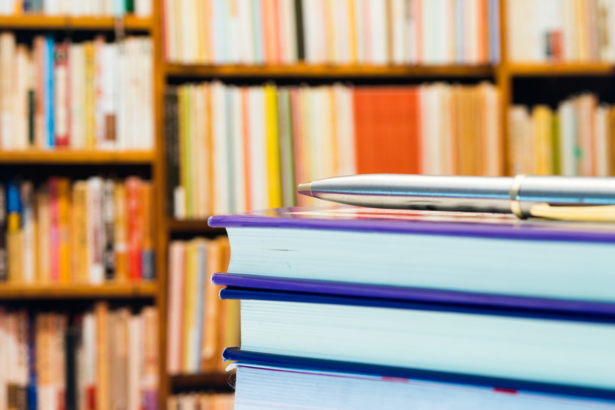 Piles of books and magazines on background of book shelf