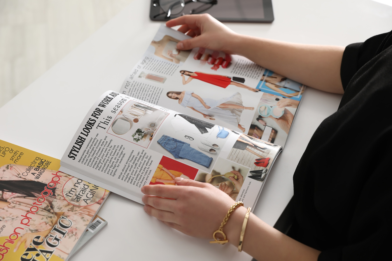 Woman Reading Fashion Magazine at White Table, Closeup